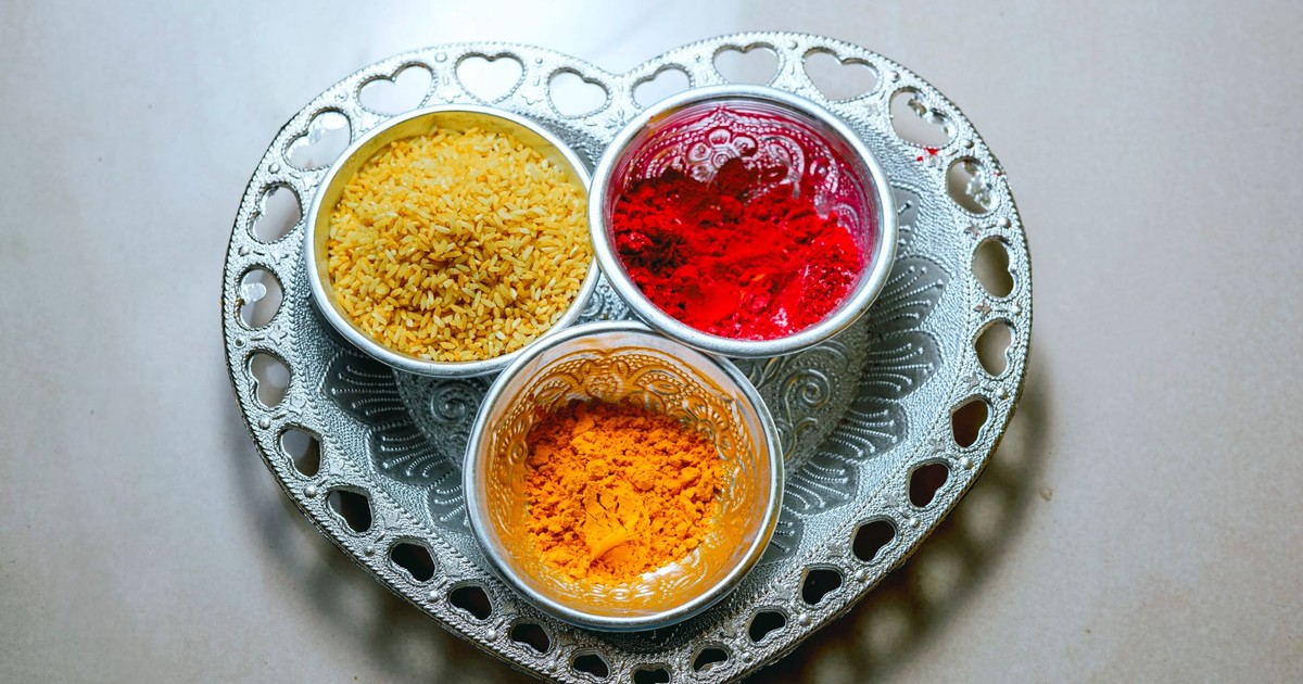 Top view of vibrant spices and rice on a heart-shaped tray, showcasing Indian flavors.