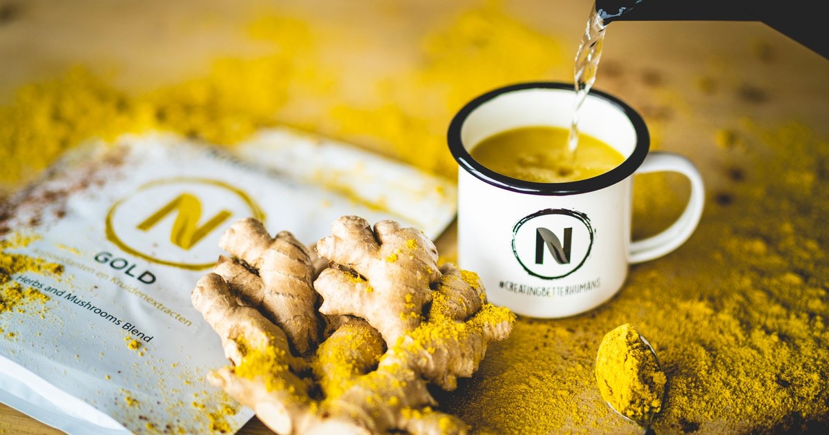 Pouring hot water into a mug with ginger and mushroom blend for a healthy beverage.