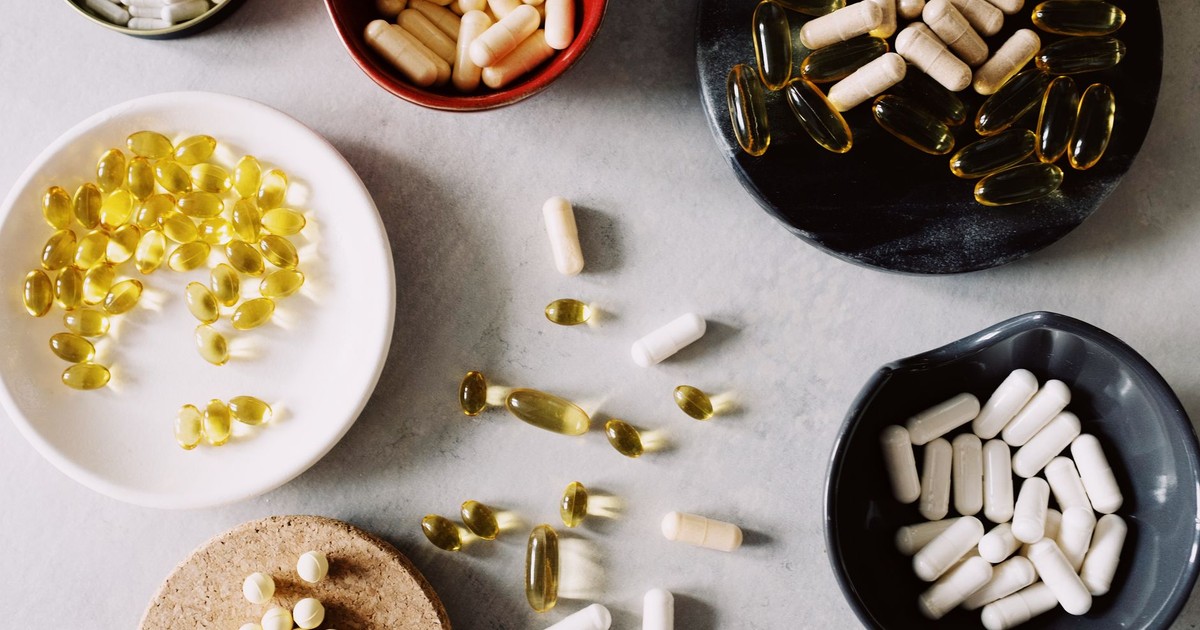 Various pills and supplements in bowls on a marble surface, ideal for healthcare contexts.