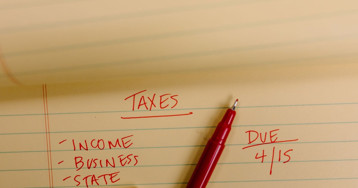 Close-up of tax-related notes on a yellow legal pad with red pen, highlighting important due dates.