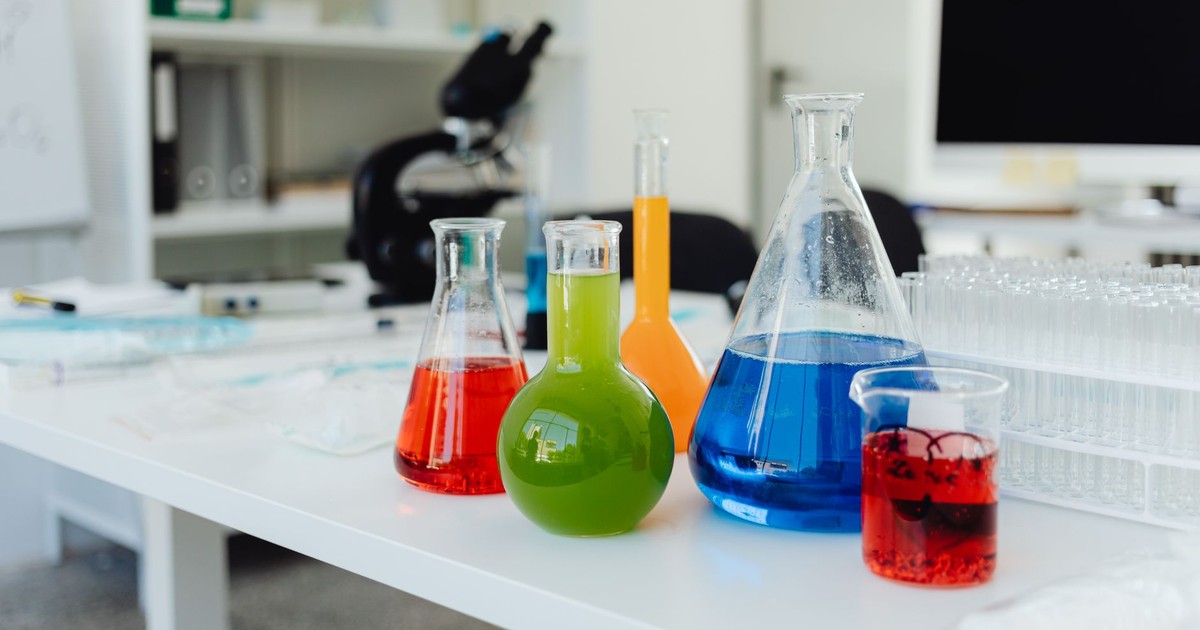 Bright, colorful chemicals in flasks and beakers on a lab table indicating a chemistry experiment in progress.