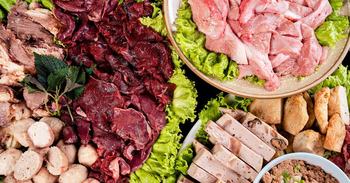 An overhead view of assorted raw meats and ingredients on platters with lettuce.