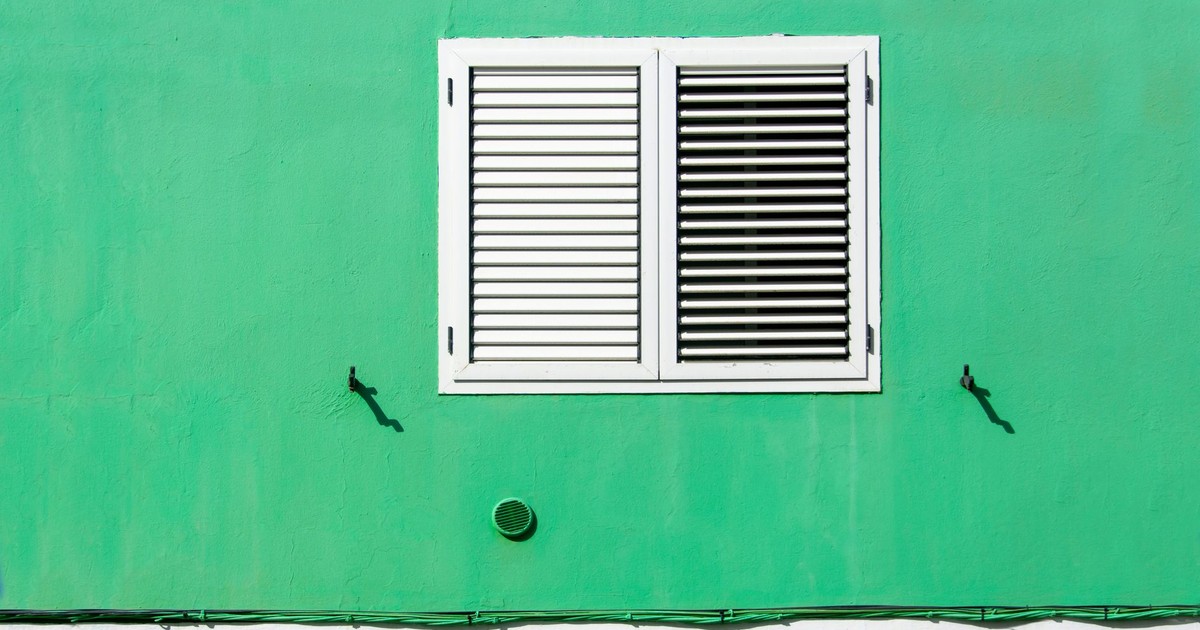 Simple yet striking green wall with white shutters creating a bold minimalist look.