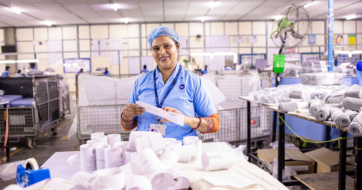 Female textile worker inspecting labels in a factory setting, showcasing blue-collar work environment.