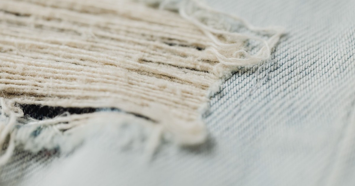 Detailed macro shot showcasing the frayed texture of a denim fabric, highlighting its woven pattern and wear.