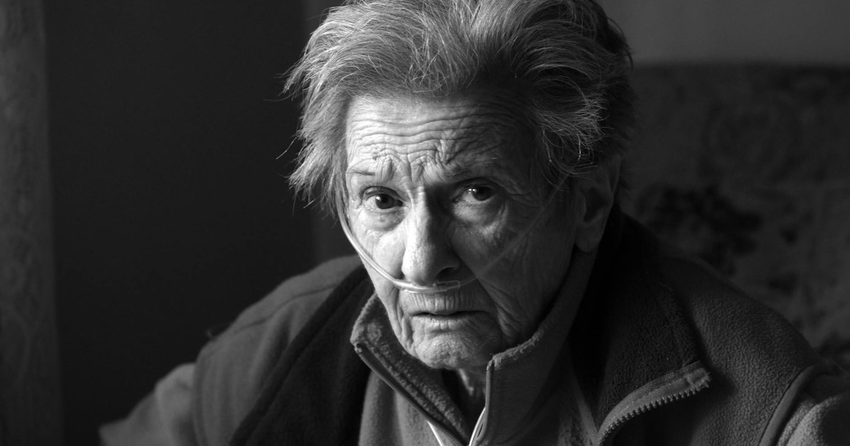 A touching portrait of an elderly woman using oxygen support, showing resilience and strength.