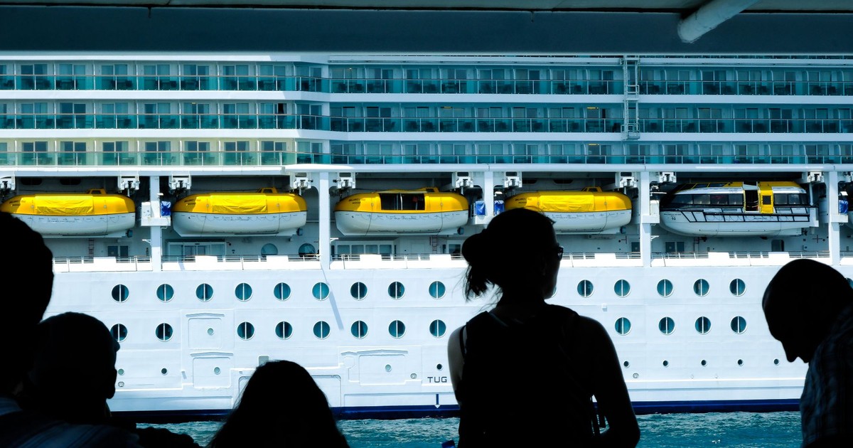 Silhouettes of people observing a large cruise ship from a dock in Türkiye.