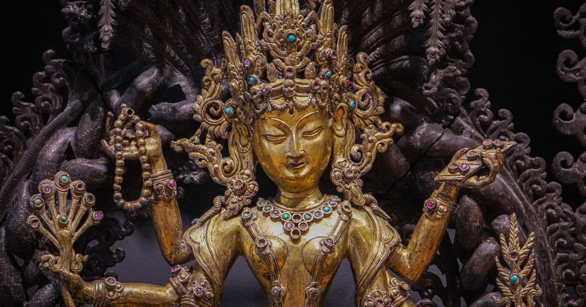 A detailed gold statue of a Hindu goddess adorned with jewels, showcasing intricate craftsmanship.