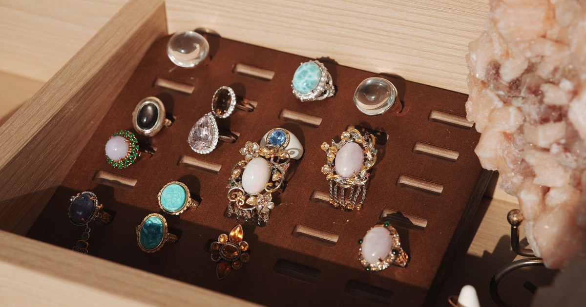 A neatly organized jewelry box showcasing various gemstone rings with a natural crystal accent.