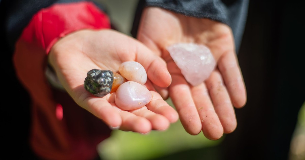 Two hands displaying vibrant gemstones outdoors in natural light.