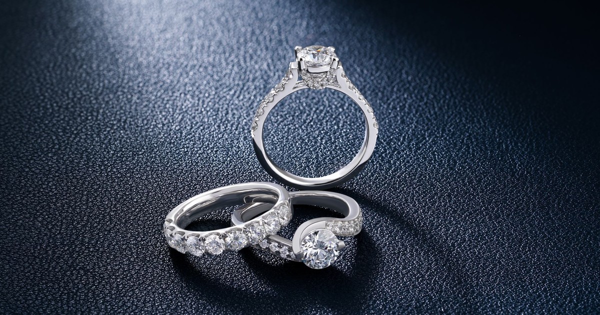 Close-up of luxurious diamond engagement and wedding rings on a textured surface, showcasing elegance and craftsmanship.