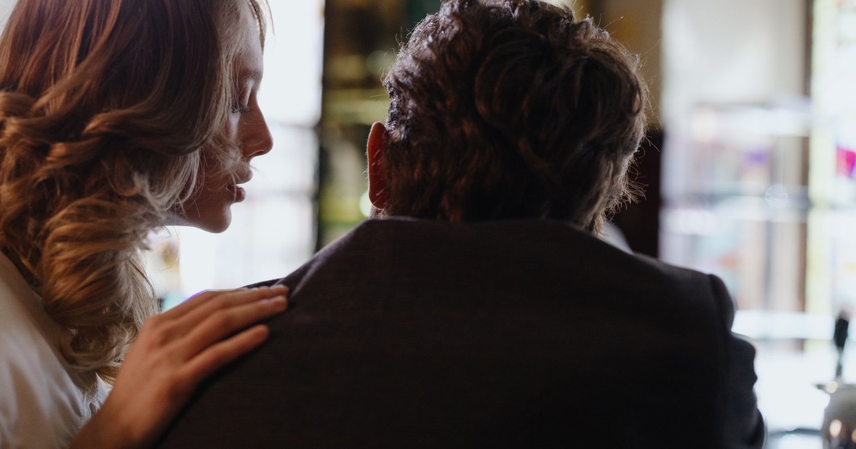 Close, intimate moment as two adults share a whisper in a softly lit room.
