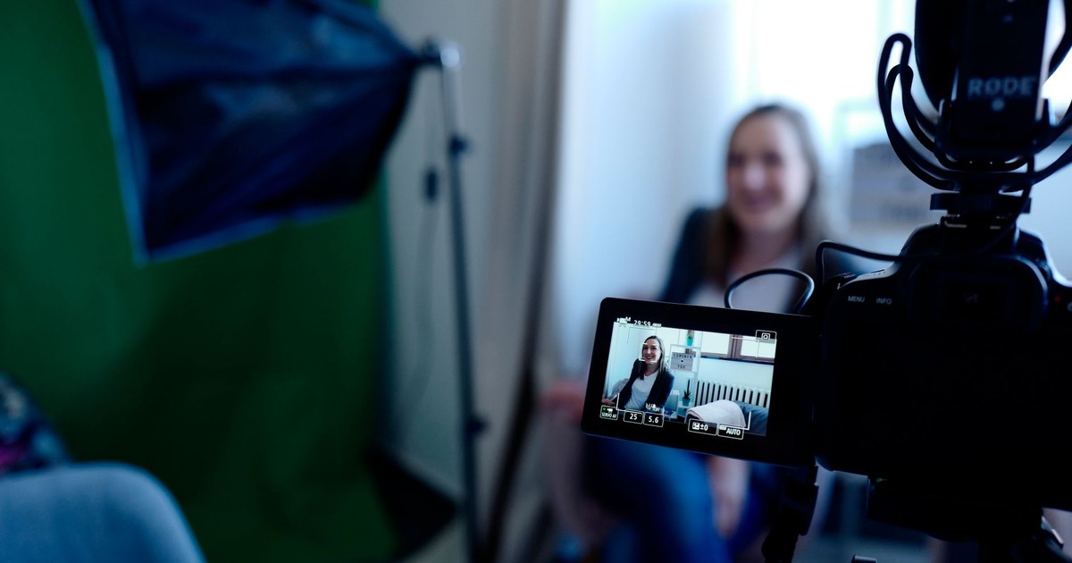 Woman being recorded in a professional studio setup, using video camera and lighting equipment.