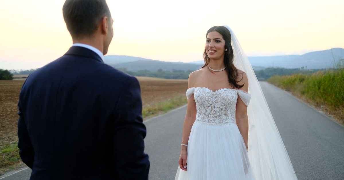 Bride and groom share a tender moment on a scenic country road, captured during a stunning outdoor wedding ceremony.
