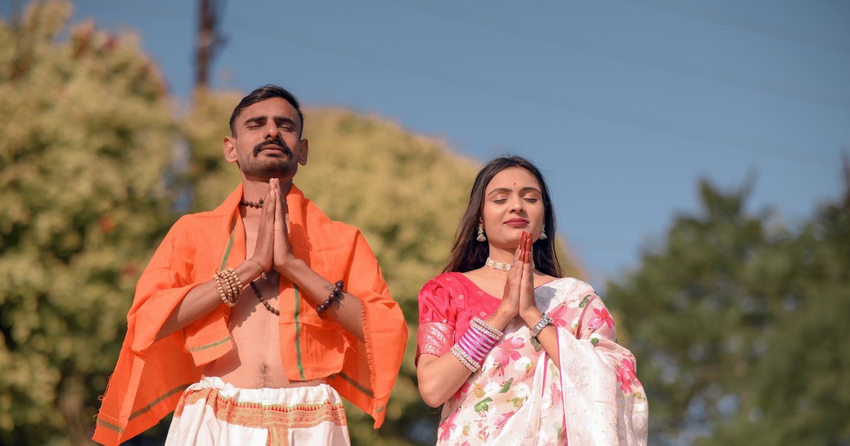 A serene Indian couple in traditional attire meditating outdoors, showcasing harmony.