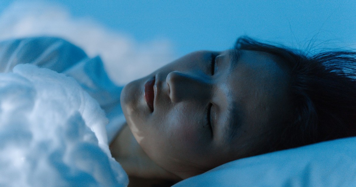 A tranquil scene of a woman sleeping comfortably on a white pillow, evoking peace.