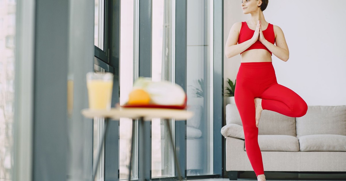 From below of content female in activewear standing on mat in living room while doing yoga exercise and looking away