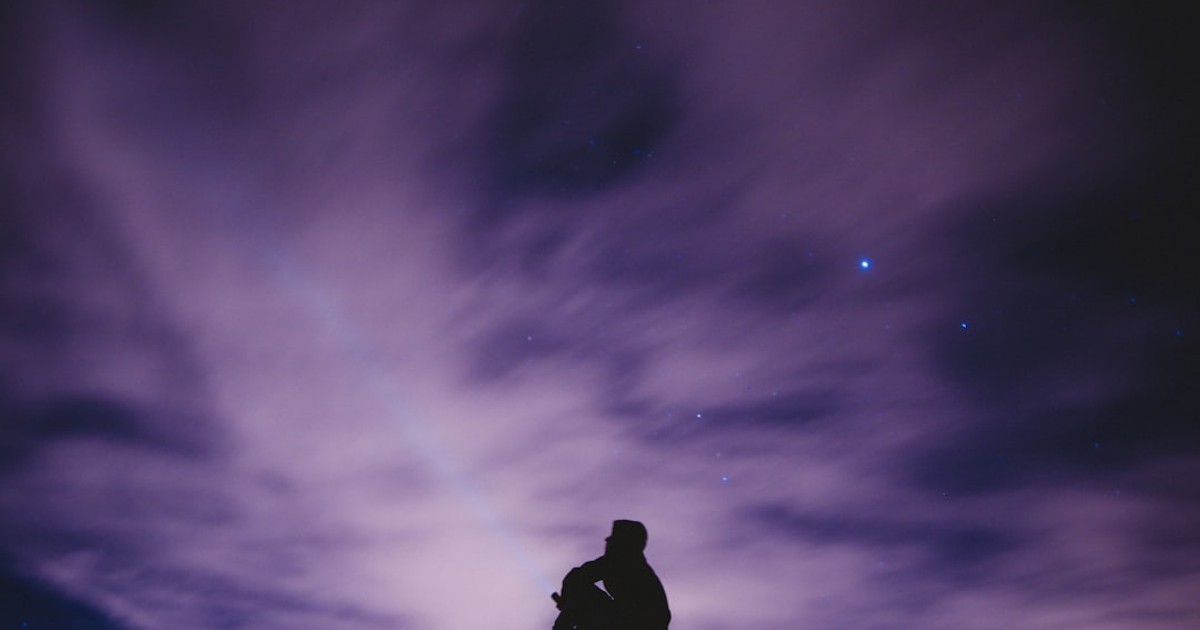 person sitting on black surface looking to sky