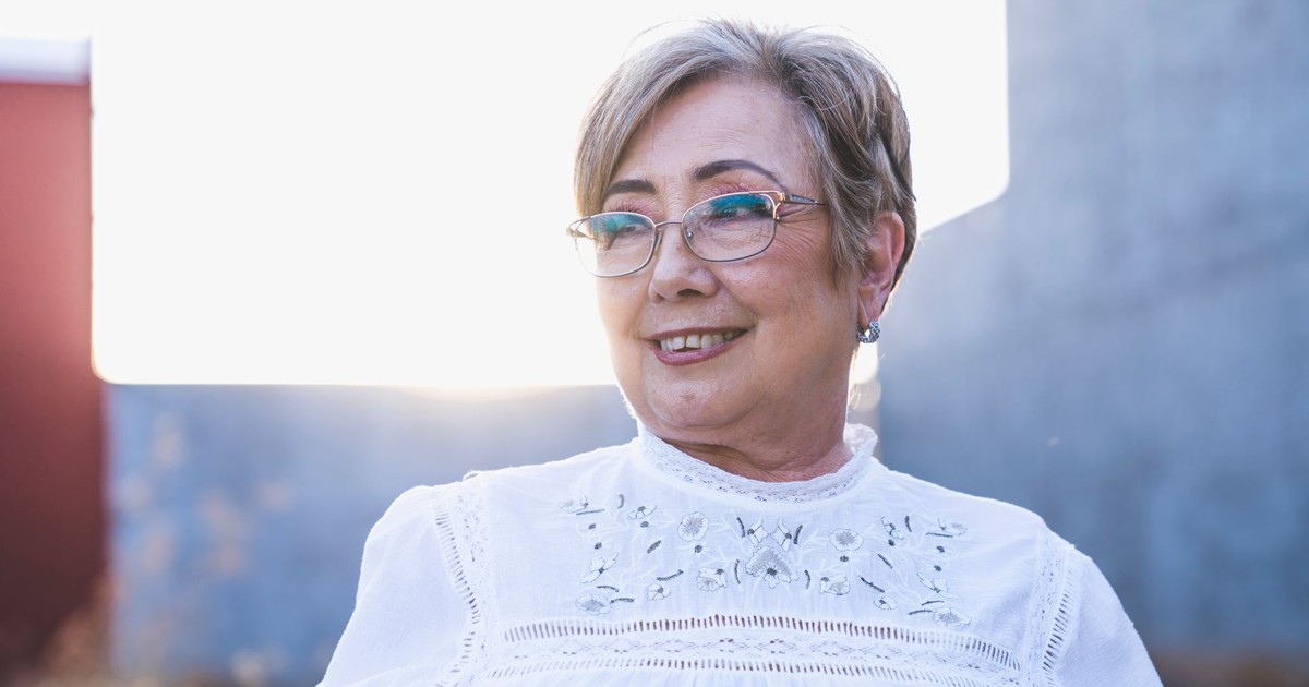 Portrait of a smiling senior woman with eyeglasses enjoying a bright outdoor setting.