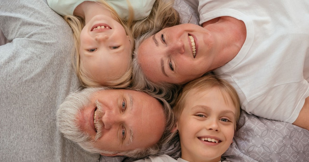A joyful multigenerational family lying down and smiling together, displaying warmth and affection.