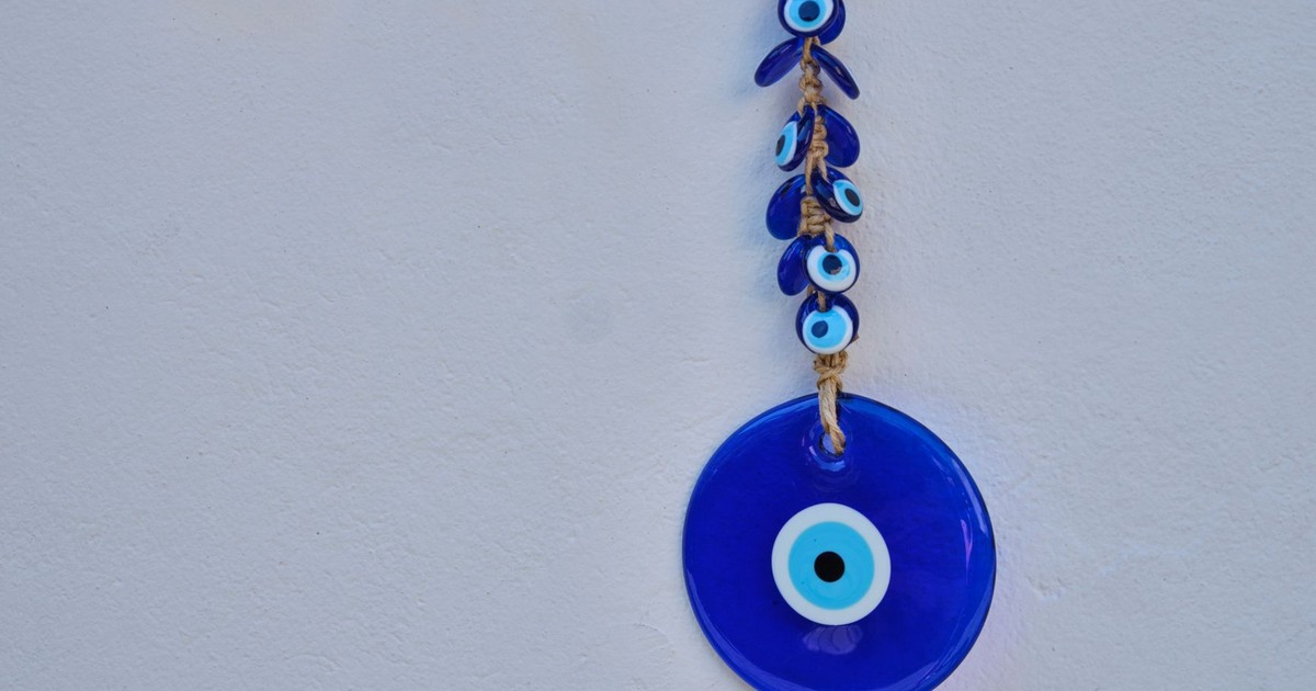 Hanging blue evil eye charm for protection and good luck on a white background.