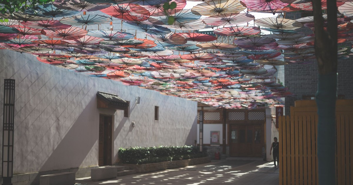 Vibrant oil-paper umbrellas suspended above a traditional Chinese courtyard.