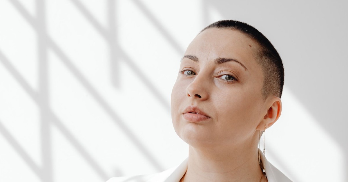 Portrait of a confident woman with short hair against a light and shadow background.