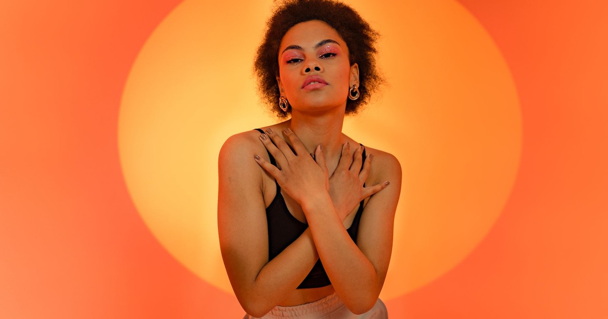 Fashionable portrait of a stylish model against a vivid orange background.
