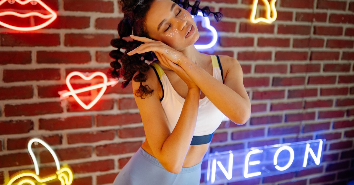 A young woman posing with creative makeup and neon lights, embracing a vibrant, artistic vibe.