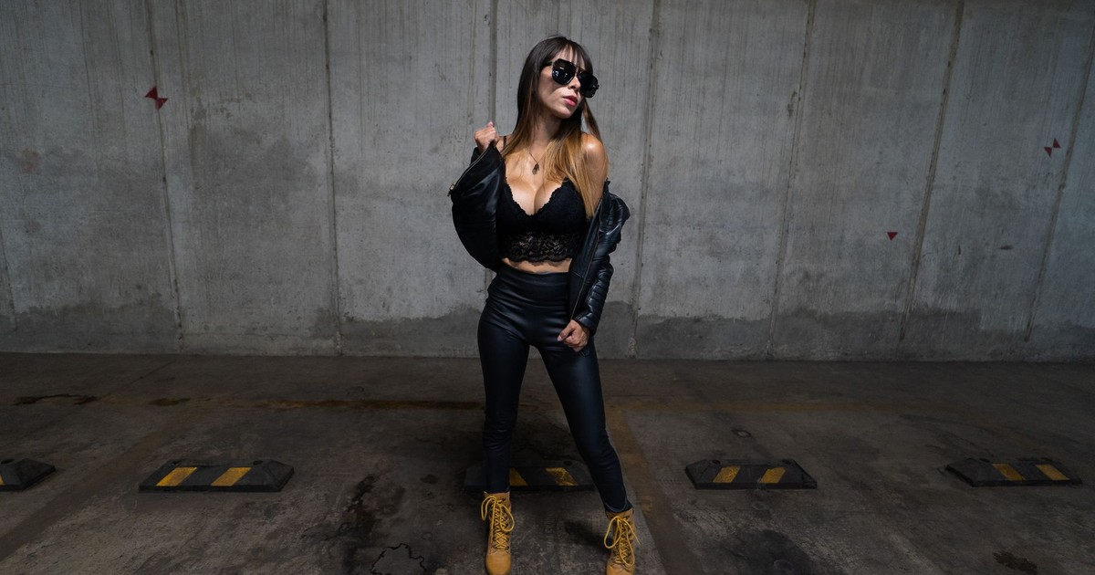 Fashionable woman in black attire posing confidently in an urban setting.