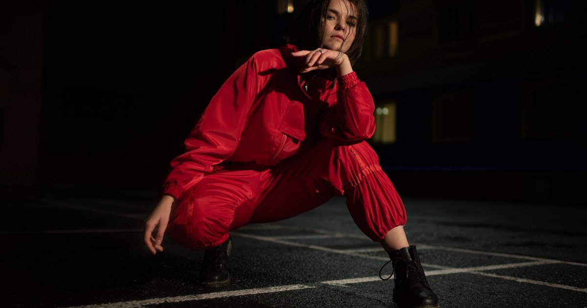 Stylish woman posing in a vibrant red outfit at night, evoking a bold and moody atmosphere.