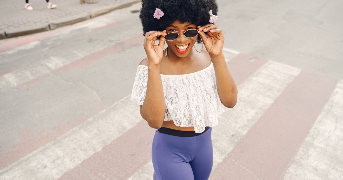 Cheerful woman with afro hair enjoying a sunny day in the city.