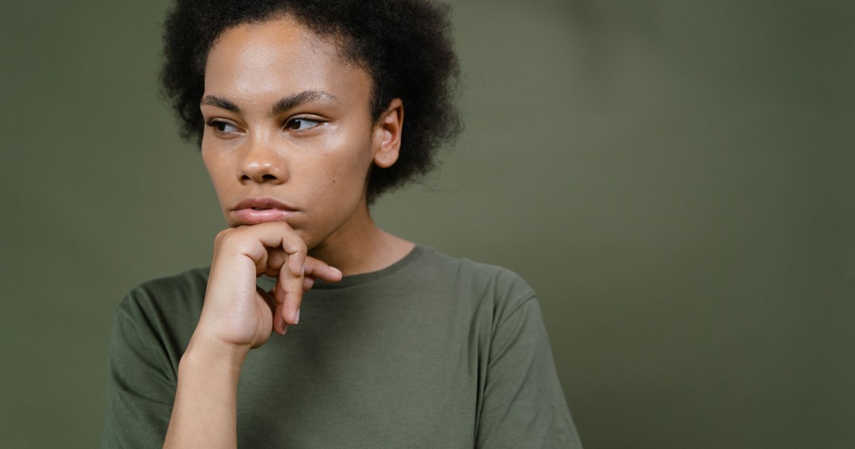 A pensive young woman with afro hair contemplating and looking away, emphasizing individuality and emotion.