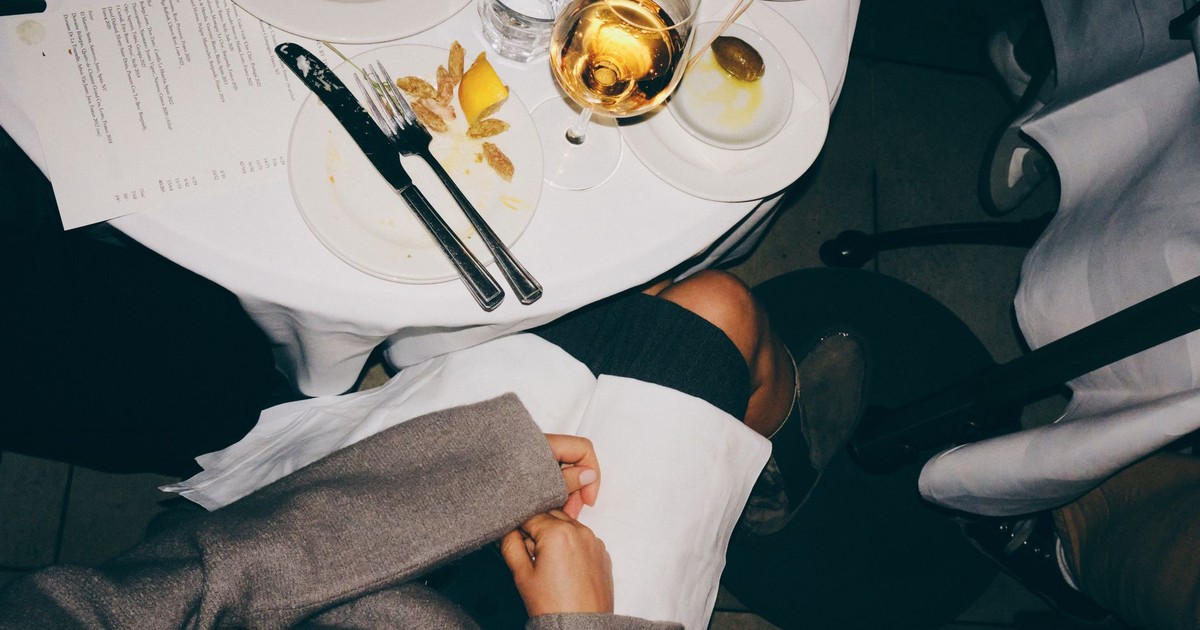 A top-down view of a dining table with elegant table setting and a glass of white wine.