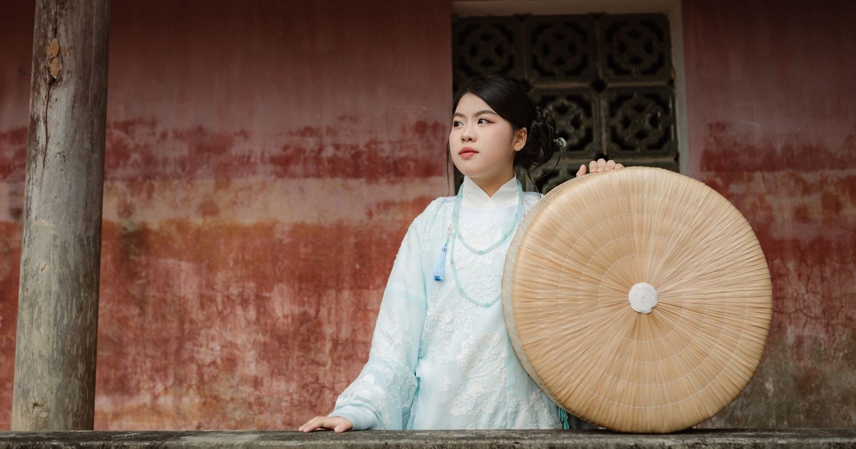 Young Vietnamese woman in traditional attire holding a round bamboo hat in Hội An.