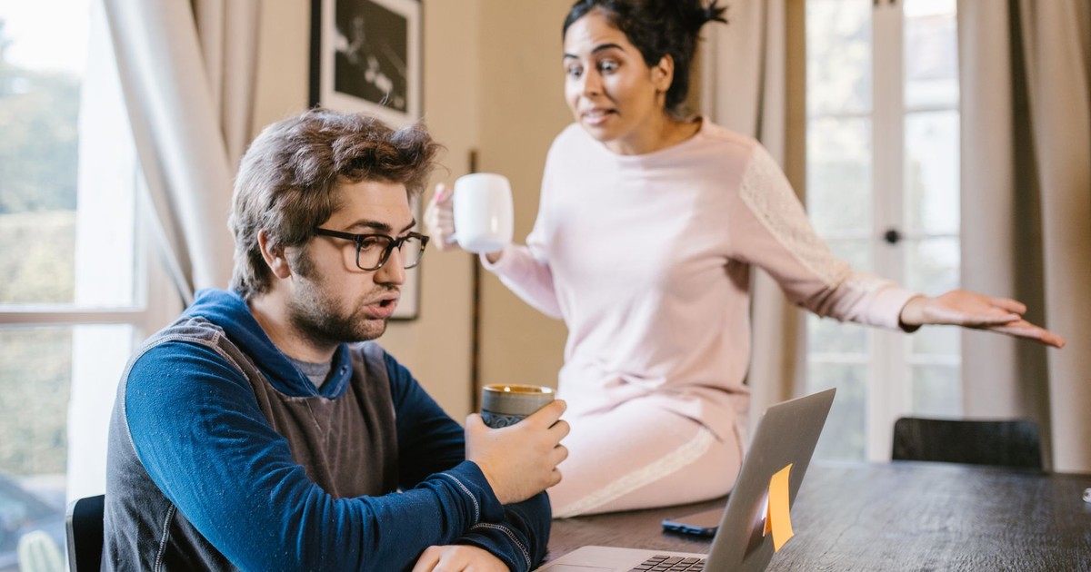 A couple having an argument at home, with a laptop on the table.