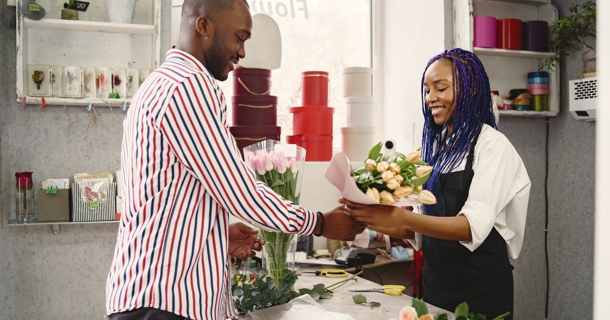 Smiling customer receiving a flower bouquet from friendly florist in cozy flower shop.