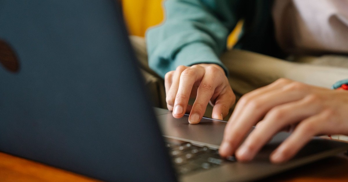 Crop unrecognizable distance employee surfing internet on netbook while working on project at desk in room