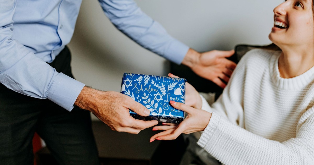 A joyful moment as a woman receives a Hanukkah gift, symbolizing love and happiness indoors.