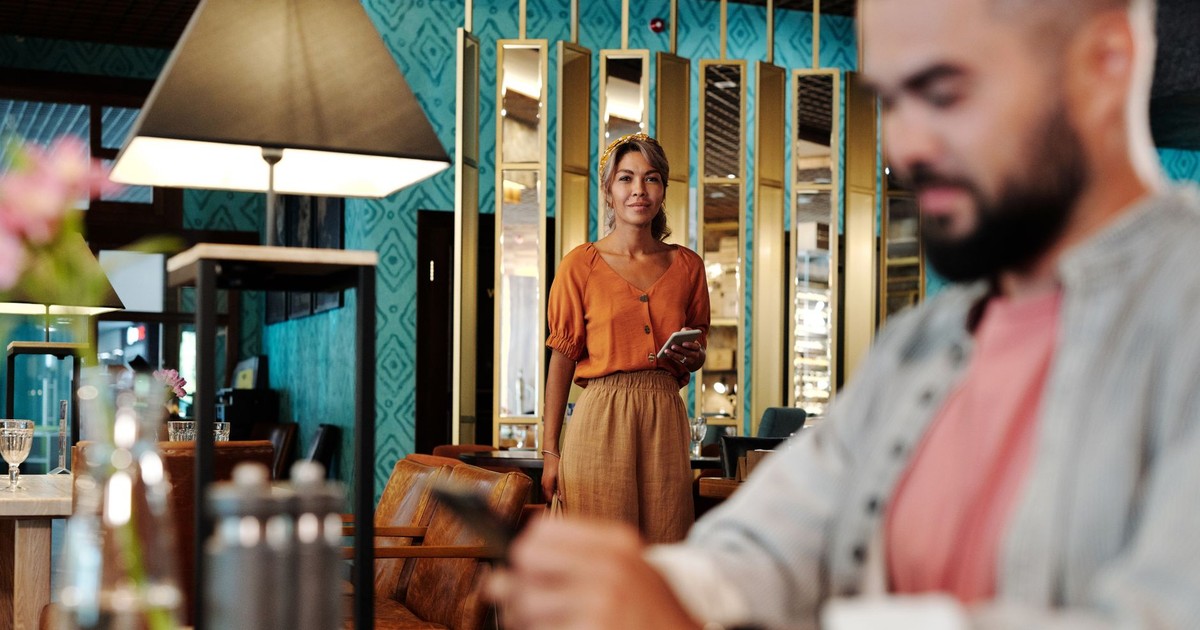 A man and woman at a modern restaurant setting, with warm interior decor.