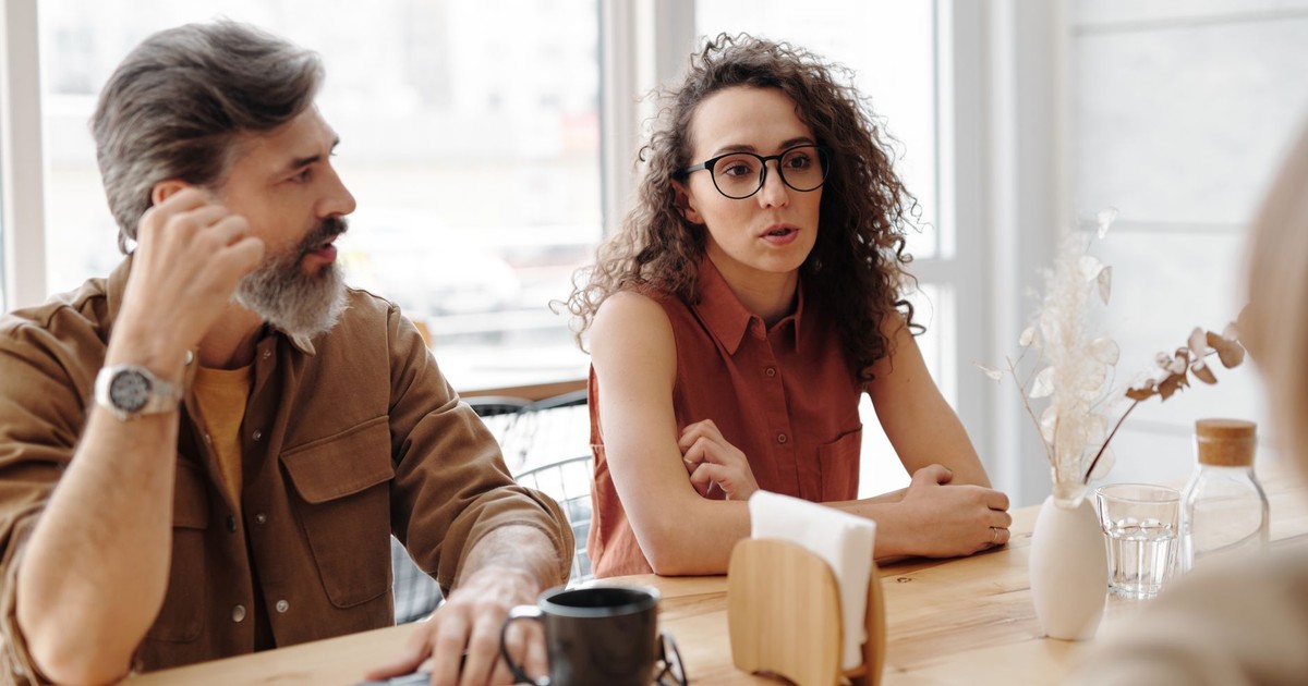Adults in conversation at a coffee shop sharing ideas and companionship.