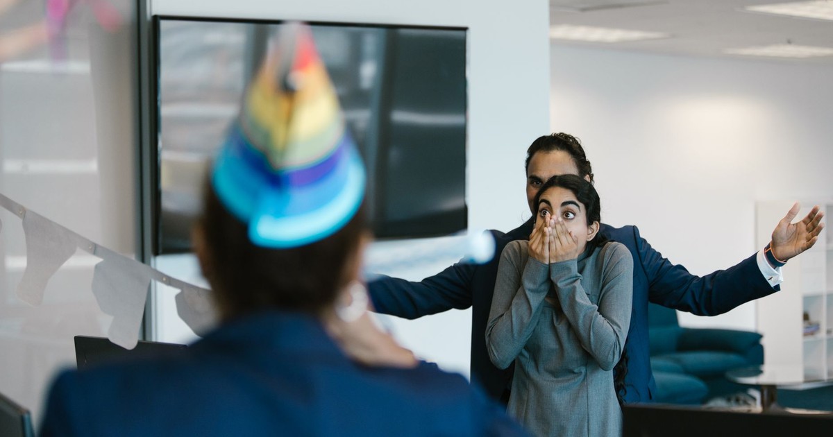 A surprised woman at an office party celebration with colleagues.