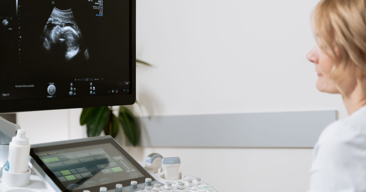 A woman undergoing an ultrasound scan by a healthcare professional.
