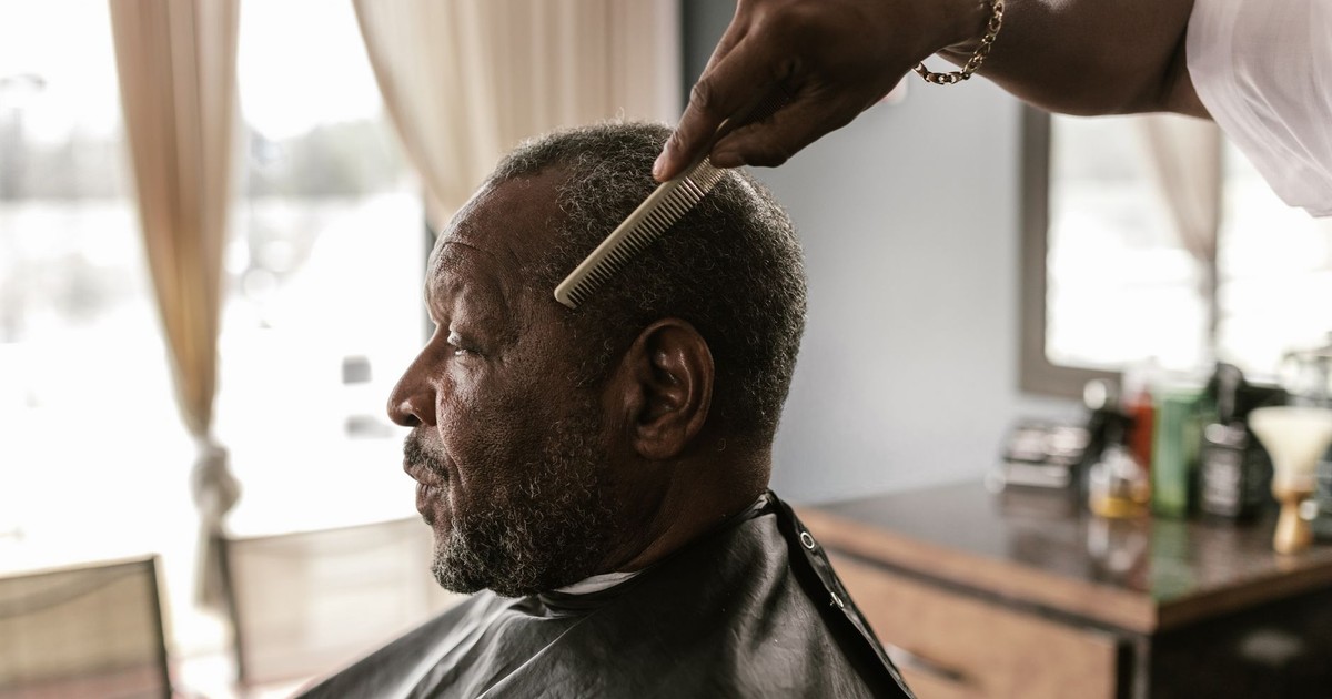 A senior man receiving a haircut at a barbershop, showcasing grooming in a classic setting.