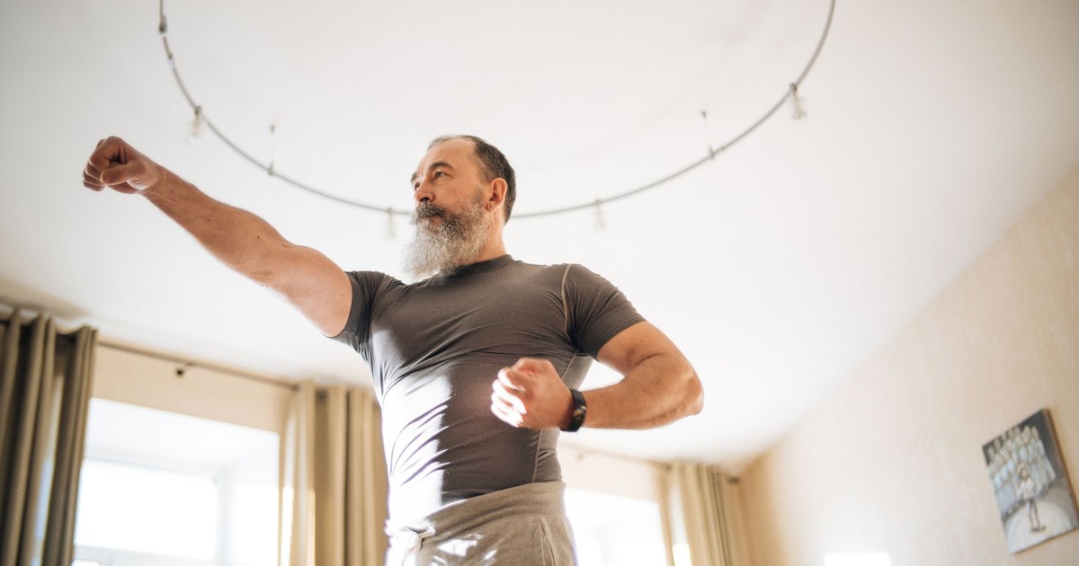 Elderly man performing yoga indoors to stay healthy. Emphasis on active lifestyle and wellness.