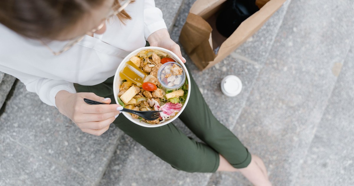 Top-down view of a woman enjoying a healthy salad outdoors during a casual lunch break.