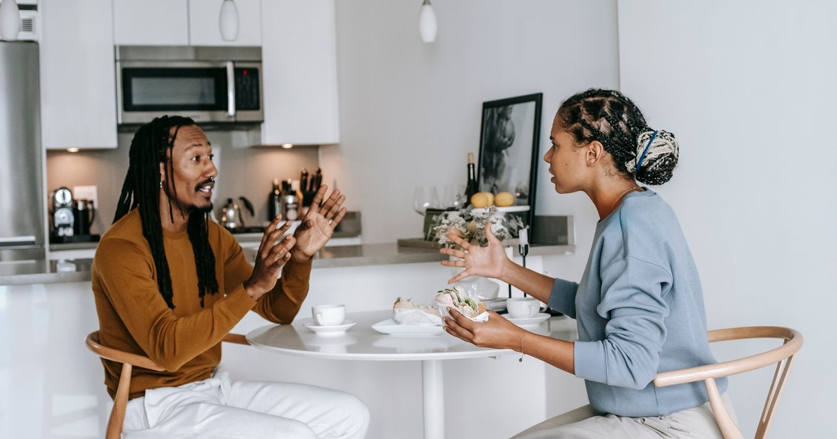 Side view of young African American male with dreadlocks in casual outfit having argument with African American 
dissatisfied female