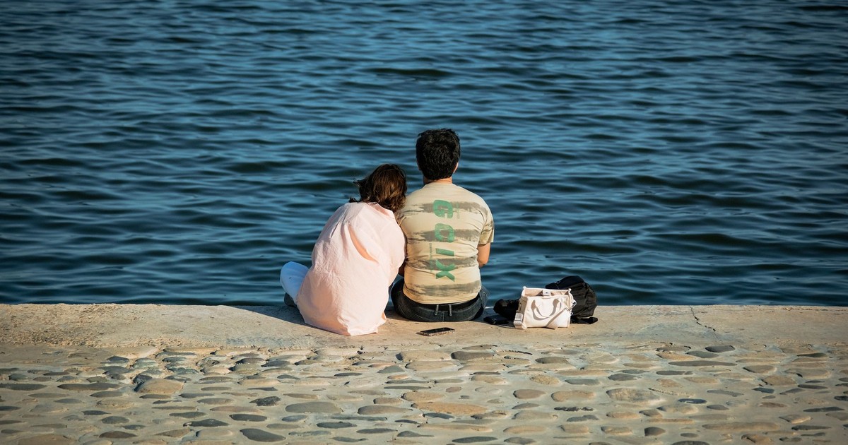 A couple sits by the water's edge, enjoying a peaceful moment together.