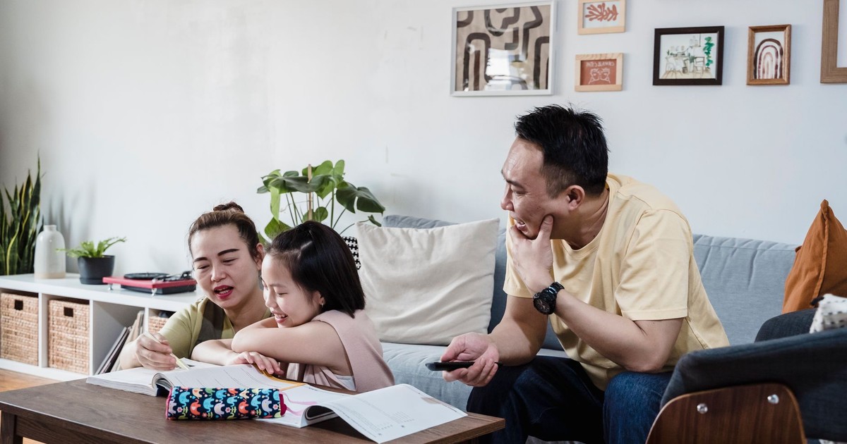 A family enjoys quality time studying and writing together in their living room.