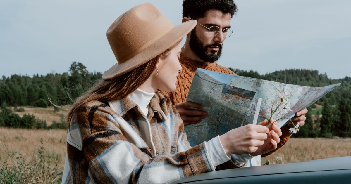 A couple outdoors examining a map, surrounded by nature, planning their adventure.